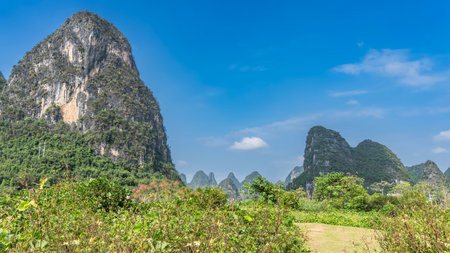 Picturesque mountain landscape. Steep high cliffs against a background of blue sky and clouds. Green vegetation in the valley. China. Yangshuo. Moon Hillの写真素材