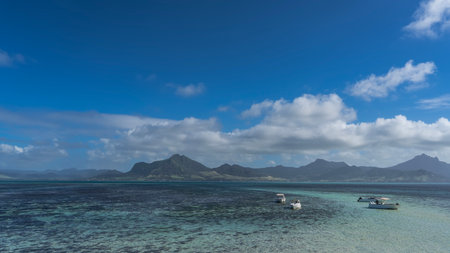 Tourist motorboats are anchored in the turquoise ocean. Corals are visible through clear water....