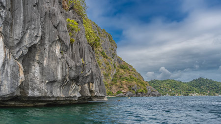 The picturesque rocky coast of a tropical island. Sheer cliffs surround the bay. Tourist canoes...