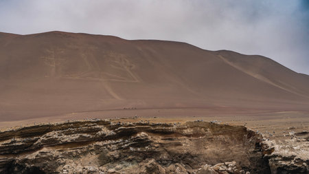 The famous Paracas Candelabra. Drawing of a huge trident on the slope of a sandy hill. Blue sky, clouds. Peru. Candelabra of the Andesの写真素材