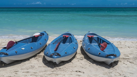 Three canoes with paddles on a sandy beach by the aquamarine ocean. The horizon above the water.. The blue sky. Cuba. Varadero.の写真素材