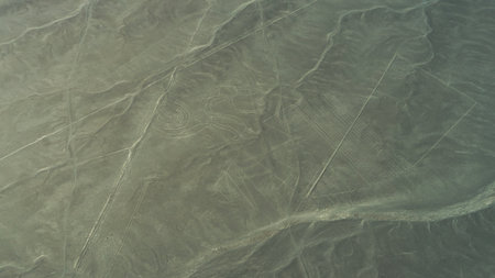 The unique Nazca lines in the desert. There is a monkey drawing and many parallel lines on the sandy...