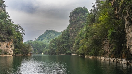 The beautiful emerald lake is surrounded by mountains. Green vegetation on steep slopes. Ripples, reflections on the water. Clouds in the sky. China. Wulingyuanの写真素材