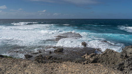 The ocean waves are raging and crashing against the coastal cliffs. White foam. The bizarre rough black volcanic rocks of the island's coast are in the foreground. Mauritius.の写真素材