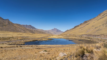 Beautiful high-altitude landscape. Alpine lake in the valley. Yellow dry grass. The railway track...