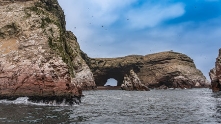 Picturesque islands in the ocean. Steep rocky slopes, natural stone arches. Birds in the blue sky. Peru. Paracas. Ballestas Islandsの写真素材