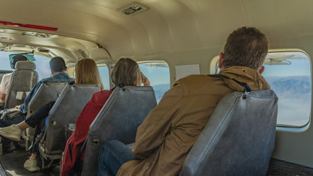 People are sitting in a row in the cabin of a small plane, looking out the windows. View from the...