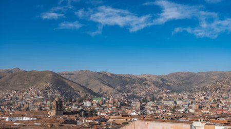 Panorama of a high-altitude city. Urban buildings in a valley surrounded by mountains. Red tiled roofs, the bell tower of the ancient Catholic cathedral. A mountain rangeの写真素材