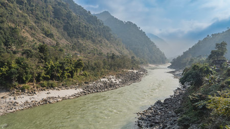 Mountain river in the gorge. Piles of boulders on the shores. The forest on the mountain slopes. Clouds in the sky. Nepal.の写真素材