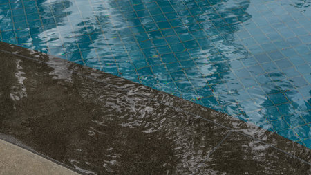 A fragment of a swimming pool. Clear, transparent, shiny water. Ripples, glare on a smooth surface. A barrier along the perimeter. Blue tiled bottom. Close-upの写真素材