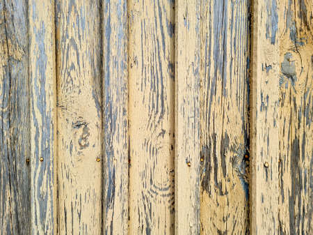 Wooden planks stacked vertically on top of each other with a row of nails, cracked yellow paint and a worn background texture. Vintage texture, patternの写真素材