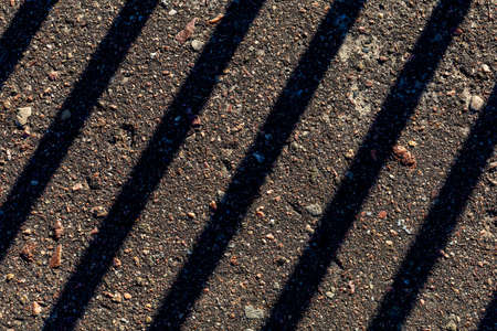 Diagonal and parallel lines of shadow on the asphalt, top view, interesting and unusual backgroundの写真素材