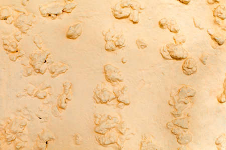 Beige background with uneven surface, protruding stones of different sizes stick out on the surface,...