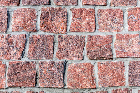 A background of square red-gray-brown similar paving stones, laid out in horizontal lines with...