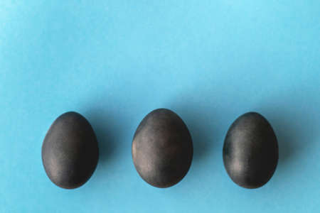 Three painted blue Easter eggs in a row on a blue background. Top view, space for textの写真素材