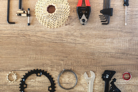 Bicycle parts and specialized service keys on a brown wooden background in two rows with copy space in the middle. Bike workshop concept with place for textの写真素材