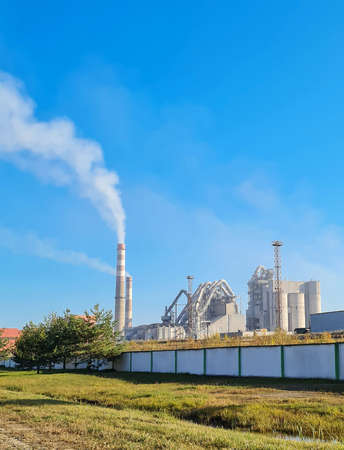 The factory spews smoke from its pipes against a backdrop of clear blue skies, pollutionの写真素材