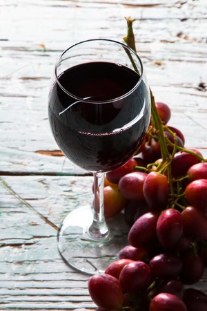 Wine and cheese on wooden table with fresh grapesの写真素材