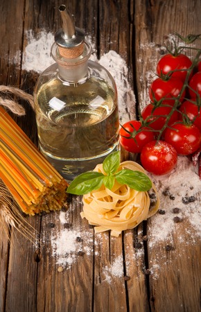 Pasta spaghetti, vegetables and spices, on wooden table, on balck stone backgroundの写真素材