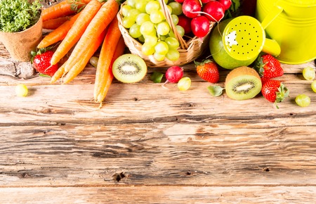 Garden concept, fresh fruits and vegetables on wooden table, watering can, seeds, plantsの写真素材