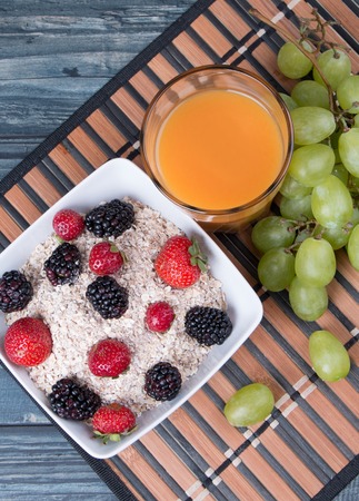 Breakfast concept with orange juice, coffee, fruits on wooden tableの写真素材