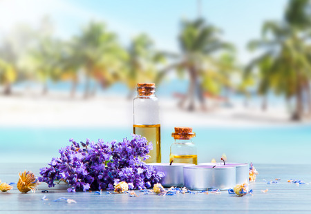 spa massage setting, lavender product, oil on wooden and tropical beach backgroundの写真素材