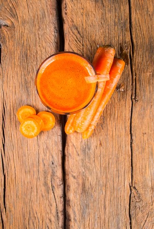 Glasses of carrot juice with vegetables on tableの写真素材