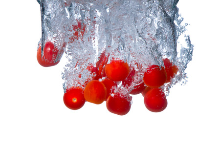 Fresh vegetable, tomato falling in water splash, isolated on white backgroundの写真素材