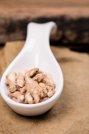 Dried ginger in white spoon on stoneの写真素材