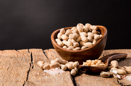 Peanuts in wooden bowl with black backgroundの写真素材