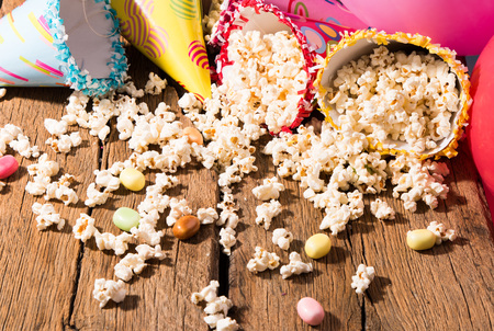 Salt popcorn, party hat and candy on the wooden table,の写真素材