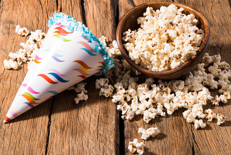 Salt popcorn, party hat and candy on the wooden table,の写真素材