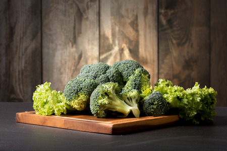Fresh broccoli on black stone with wooden backgroundの写真素材
