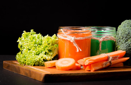 Fresh green and carrot smoothie in glass on the black stone. Lifestyle conceptの写真素材