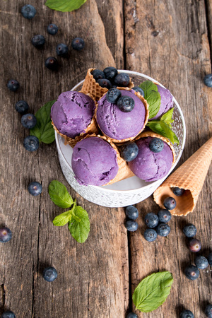 Ice cream, Blueberry ice cream scoop in cone on wooden table.の写真素材