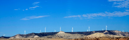 Wind turbines on a mountain range against a blue sky. Renewable energy, wind power, and a clean...