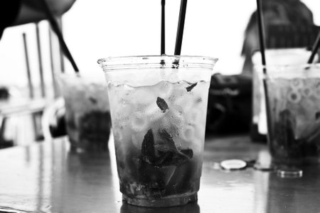 Close-up of a drink in a clear cup with ice and mint leaves. Black and white, detail-oriented, and blurred background.の写真素材
