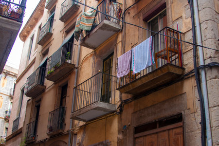 Aged building facade with balconies and wrought-iron railings. Girona, laundry, and urban authenticityの写真素材
