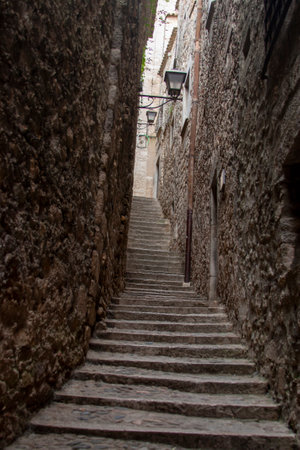 Tall, textured stone walls framing a narrow stairway. Medieval setting, cobblestone steps, and perspectiveの写真素材