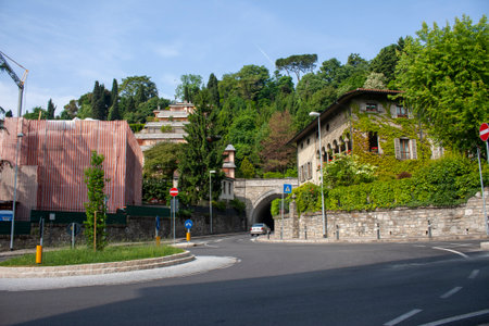 Intertwined nature and architecture with vine-covered buildings and green hills. Road with a roundabout and street signsの写真素材