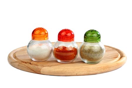 Isolated salt, black pepper and paprica boxes  on wooden plate on white backgroundの写真素材