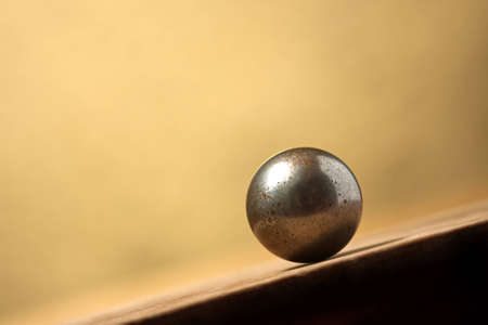 Vintage metal ball on sloping surface over yellow background  Copy spaceの写真素材