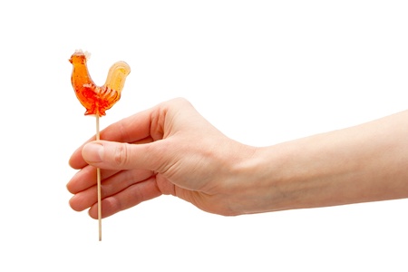 Sweet cockerel on stick in hand isolated on whiteの写真素材