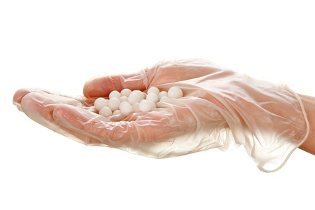 White pills on woman's palm in disposable glove isolated on white backgroundの写真素材