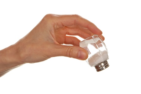 Female hand holding salt cellar upside down isolated on white background