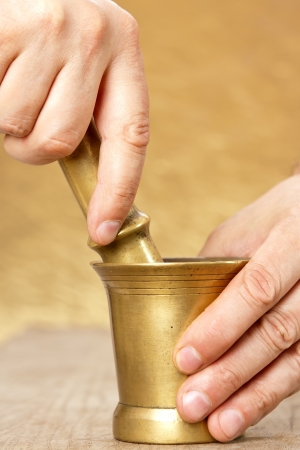 Close up of man hands with mortar and pestle on yellow backgroundの写真素材