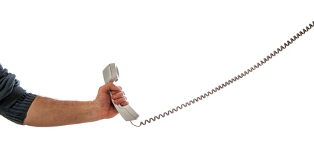 Male hand holding wired phone isolated on white backgroundの写真素材