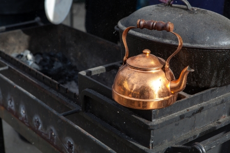 Old bronze teapot on black grill surounded by smoke and ash dust の写真素材