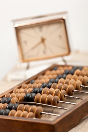 Close up of a wooden abacus beads,vintage clock face is seen on background. Selective focus, shallow depth of fieldの写真素材