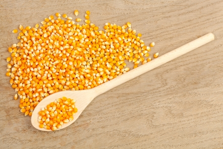 Spoon with corn grain on a wooden tableの写真素材